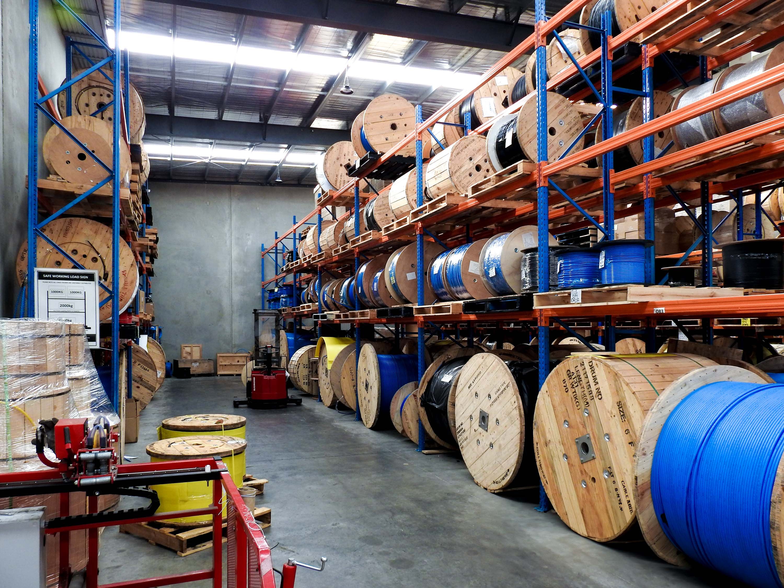 Multiple fiber cable drums in an indoor warehouse.