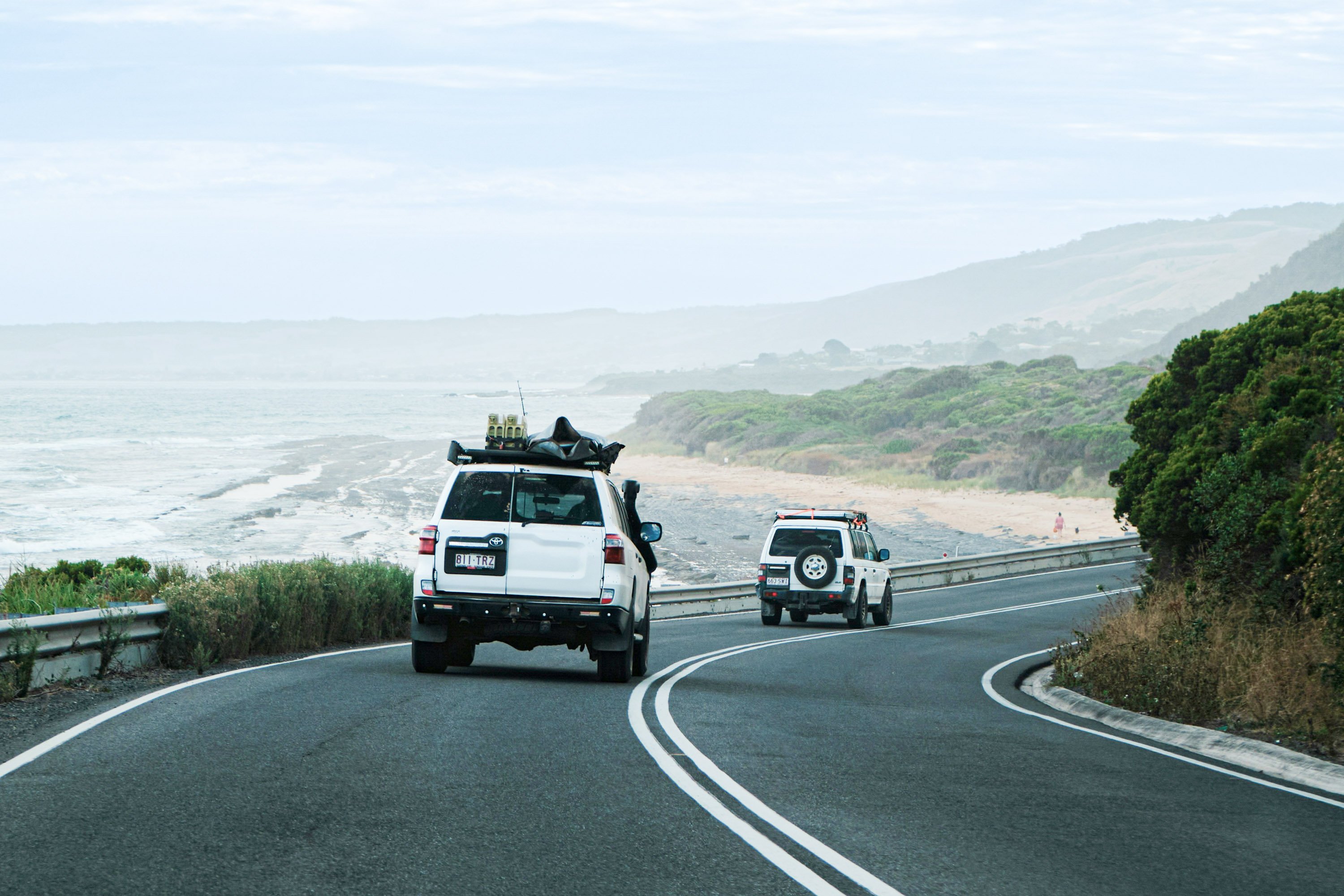 Two white jeeps driving on an ocean road in Australia.