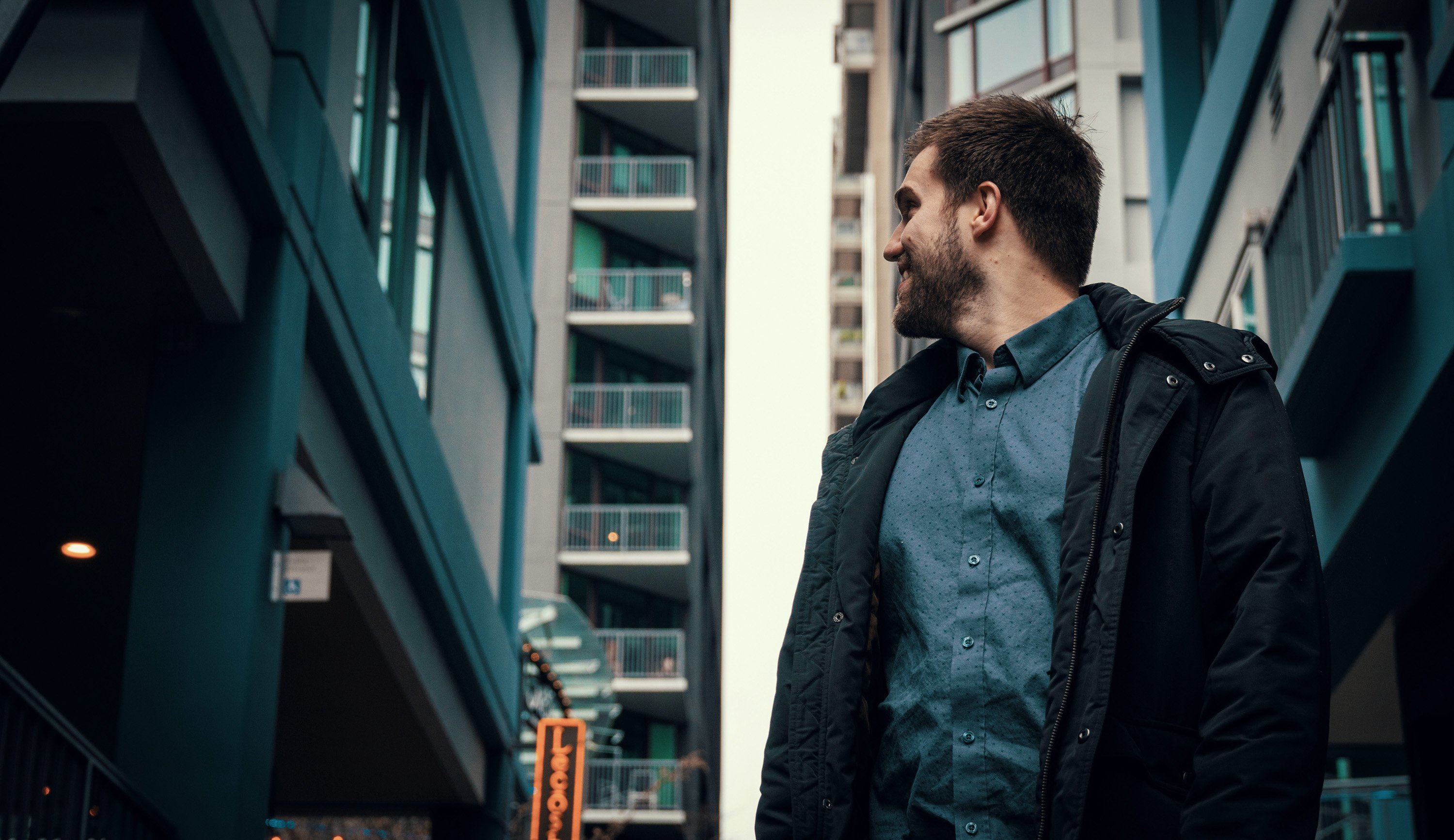 A smiling person in a city center looking over his shoulder